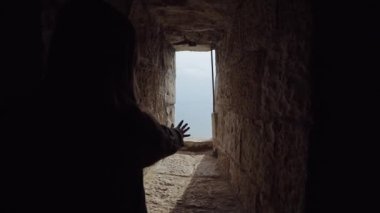 Kız büyük kale duvarının küçük bir pencerede karanlıktan güneşe elini alır