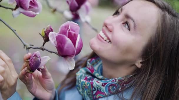 Vacker söt flicka i överraskning tittar på en stor vacker blomma av rika rosa färg i närbild — Stockvideo