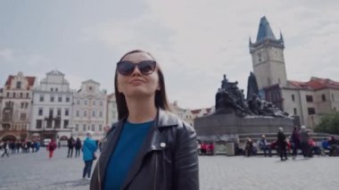 Güneş gözlüğü şık genç kız Prag Old Town Meydanı'nda yürüyor, Çek Cumhuriyeti. Arka planda Jan Hus Anıtı var. Beatiful güneşli bir gün. Prag'da Güzel Genç Kadın Turist
