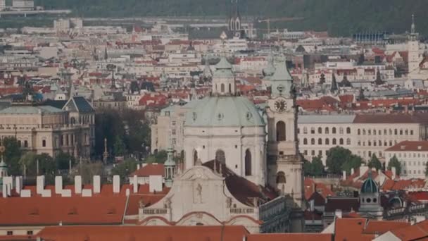 Bela vista do topo da mais famosa igreja barroca de Praga a Igreja de São Nicolau e telhados tchecos tradicionais. Plano geral — Vídeo de Stock