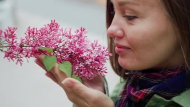 Pembe leylak kokusundan hoşlularken güzel bir kadın. Sevimli model ve çiçekler. Aromaterapi ve bahar