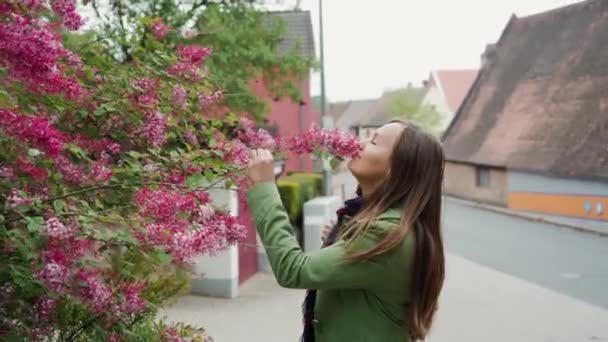 Güzel genç kadın açık havada çiçek açan pembe leylak çalı yakınında — Stok video