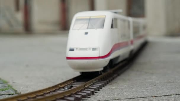 Model of high speed electric express train rides on model of railway on a city street — Stock Video