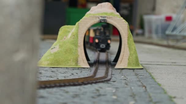 Mehrfarbiges Modell der Lokomotive bewegt sich durch den gelben Spielzeugbogen oder Tunnel, aus nächster Nähe — Stockvideo