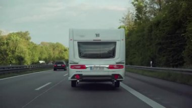 Beyaz kamp karavan yolda sürmek. Almanya. Geri görünüm