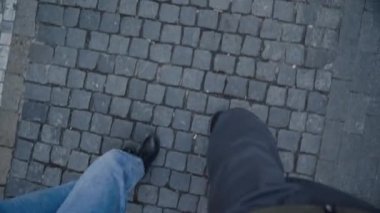 adam ve kız Arnavut kaldırımlı sokak boyunca yürüyorlar, yukarıdan görünümü, sadece bacaklar