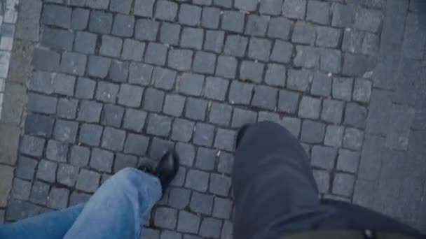 guy and girl are walking along cobbled street, view from top, only legs