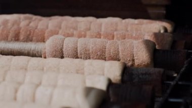 Trdelnik yakın çekimde. Tatlı tüpler sokakta pişirilir, ateş üzerinde sıcak çubuklar üzerinde dönen