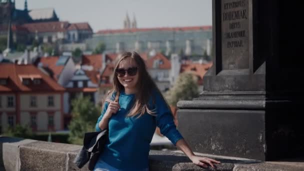Piękna dziewczyna w okularach przeciwsłonecznych stoi na mostku i uśmiecha się — Wideo stockowe