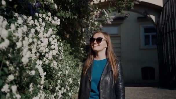 Härlig tjej går längs blommande vägg i parken på våren solig dag — Stockvideo