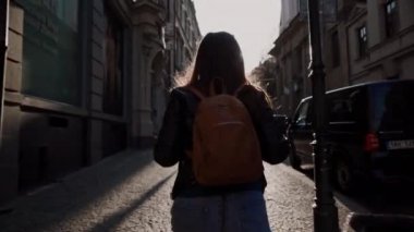 Prag, Mayıs 15, 2019: uzun saçlı ve sırt çantası ile esmer akşam güneş ışınları eski şehrin rahat sokaklarında yürür, Prag, Çek Cumhuriyeti. Geri görünüm