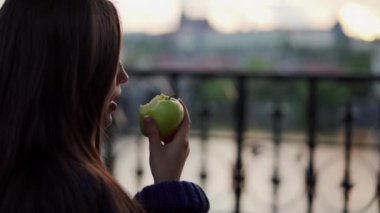 uzun saçlı esmer bulanık cityscape arka planda yeşil elma ısırır