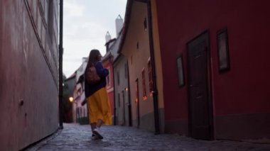 güzel kız akşam eski Prag dar renkli sokakta tek başına yürür, geri görünümü