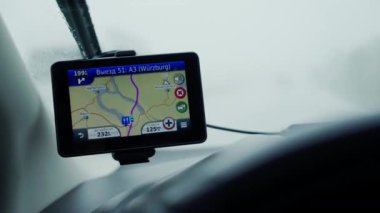 GERMANY, MAY 4, 2019: GPS Navigator on the windshield of the car in rainy day. Travel wih the Navigator. Using tablet for GPS navigation to the destination. Using modern technologies in transport