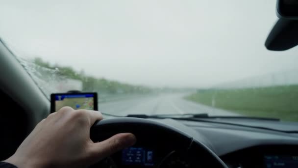 Hombre sosteniendo el volante, conduciendo un coche bajo la lluvia, conducción cuidadosa en días lluviosos, conducción de la mano izquierda, de cerca — Vídeo de stock