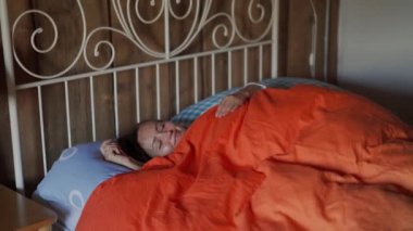 Güzel genç bir kadın yatak odasında uyanıyor. Uyku zamanı. Renkli yatak takımları