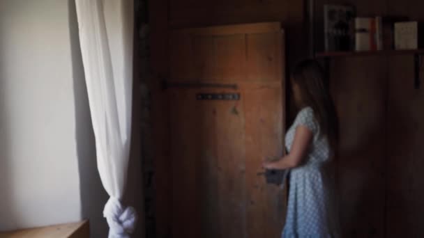 Schattig meisje in polka-dot jurk opent oude houten deur en binnenkomt kamer — Stockvideo