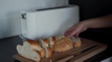 Beyaz tost makinesine bir parça tam buğday ekmeği koyan bir kadın. Kapat.