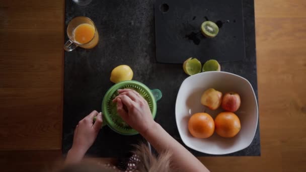 Uzavřít ženskou ruku rotující část kiwi na elektrickém lisu. Top view preparing healthy breakfast — Stock video