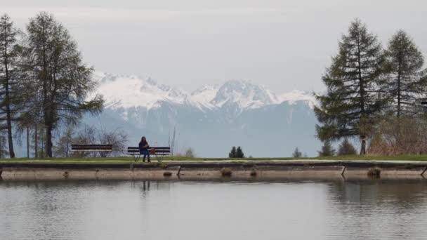 Chica turística se sienta en un banco de madera junto a un lago de montaña y mirando el mapa. Plan general — Vídeos de Stock