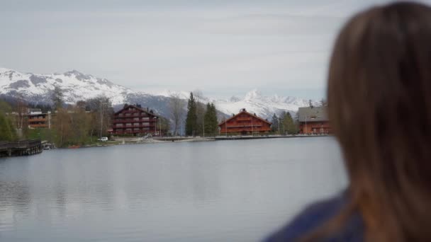 Donna che gode di una vista mozzafiato sul lago e sulle montagne e rilassato nella soleggiata giornata primaverile. Vista posteriore. Transizione focale — Video Stock