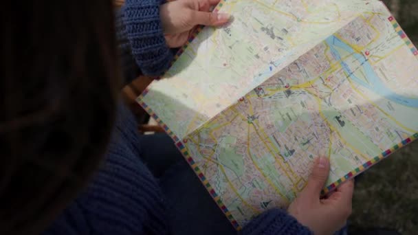 Femme tenant la carte entre les mains. Touriste à la recherche d'un emplacement de destination sur une carte papier, pointant vers des endroits. Ferme là. Vue du dessus — Video