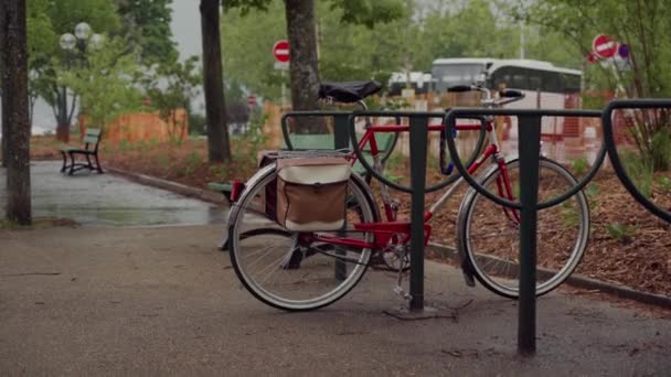 Retro rode fiets met fietstas geparkeerd op fiets parkeren wordt nat in de regen — Stockvideo