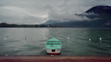 Issız nane teknesi, Annecy Gölü 'nün kıyısına demirlemiş sisli dağlarda yağmurlu günlerde arka planda