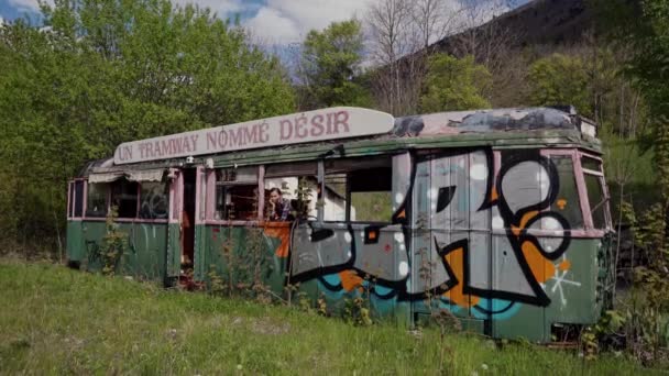 Frankrijk - 9 mei 2019: Jonge vrouw kijkt uit tramraam op bergachtige achtergrond. Oude graffiti tram genaamd Streetcar Genaamd Verlangen, vertaling uit het Frans. Straatkunst — Stockvideo