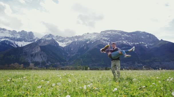 アルプスの山の牧草地で手をつないで旋回する魅力的なカップル。遠くの計画 — ストック動画