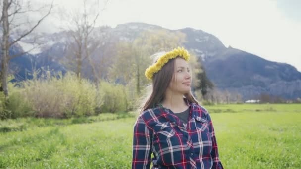 Ρομαντικό πορτραίτο ενός όμορφου κοριτσιού με στεφάνι πικραλίδας. Όμορφη κοπέλα στέκεται σε ένα φόντο βουνών — Αρχείο Βίντεο