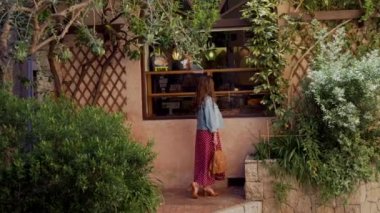 Kırmızı elbiseli romantik kadın, Fransa 'nın Antibes kentindeki geleneksel pastanenin vitrinini ya da vitrinini arıyor.