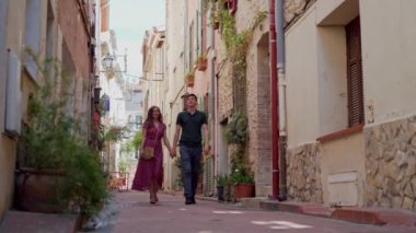 Sevgili çift Fransa 'nın Antibes şehrinde el ele tutuşup gülümsüyor. Uzak plan