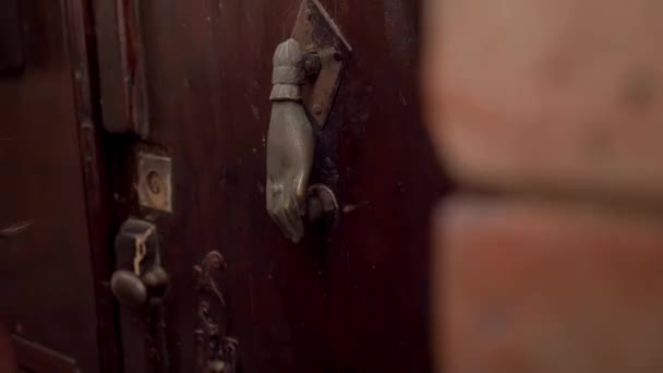 La mano femenina sostiene la puerta en forma de mano situada en la antigua puerta de madera medieval. De cerca. — Vídeo de stock