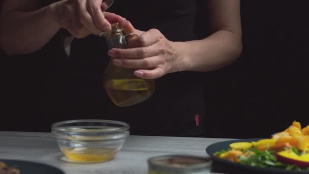 女性はサラダのソースを準備し ソースに油を追加します 暗い背景で 家での食事 — ストック動画