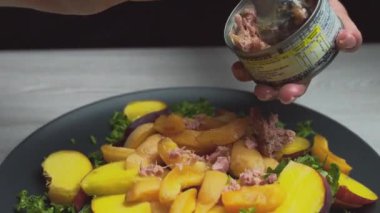 Şeftalili ve sebzeli salata. Kadınların elleri kapalı. Salataya ton balığı, et ekle.