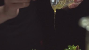 Çok iştah açıcı bir salata, üzerine sos serpiştirilmiş bal, yağ, masanın üzerinde siyah bir tabak. Vejetaryen yemekleri, sebzeler ve meyveler.