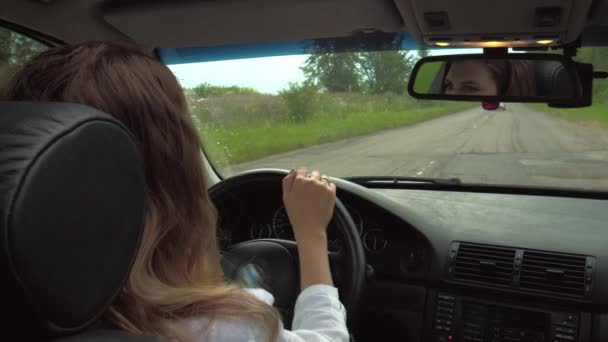在城市的道路上 女司机手握方向盘 没有模糊的道路背景 手牵着一个女人从后座上驾驶一辆汽车 — 图库视频影像
