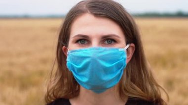Kadın kendini koronavirüs salgınından ve buğday veya arpa tarlasının ortasında salgından korumak için maske takıyor. Covid-19 ve SARS-CoV-2 enfeksiyonlarını durdur.