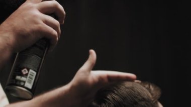 Berber müşterilere saç spreyi sıkar.