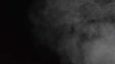 Siyah arka planda beyaz su buharı. 4K 'ya yakın çekim. Siyah Arkaplanda Gerçekçi Atmosferik Gri Duman. Beyaz Duman Yavaşça Yükseliyor. Soyut Haze Bulutu. Animasyon Buğusu Efekti. Duman Akımı Efekti 4K