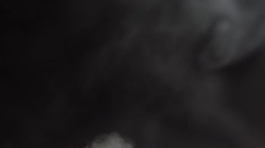 Beyaz Buhar Pan 'ın üstüne çıkıyor. Beyaz Buhar perde arkasındaki büyük bir çömlekten yükseliyor. Siyah arka plan. Bir hızda çekilir