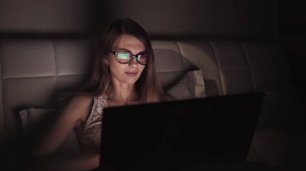 Nøkkelbrett for forretningskvinne på bærbar datamaskin som jobber overtid om kvelden, kvinnelig ekspert som leser nettsider innen tidsfristen – stockfoto