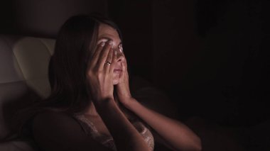 Genç kız bir dizüstü bilgisayarla kanepede uzanıyor ve birkaç kez esniyor. Geceleri çalışmaya çalışıyorum. Uzun saçlı ve beyaz gömlekli bir kız. Bacakları ekoseyle kaplı.