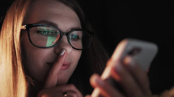 Belle jeune femme allongée au lit, utilisant un téléphone intelligent et souriant avant de dormir. Femme utilisant un téléphone portable sur le lit la nuit. Fille attrayante à la recherche de téléphone mobile. — Photo