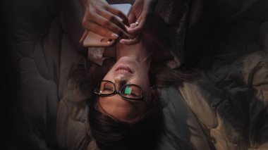 Sinsi internet sörfü. Akıllı telefondan sosyal ağda sörf yapan güzel hacker kız mesaj gönderiyor.