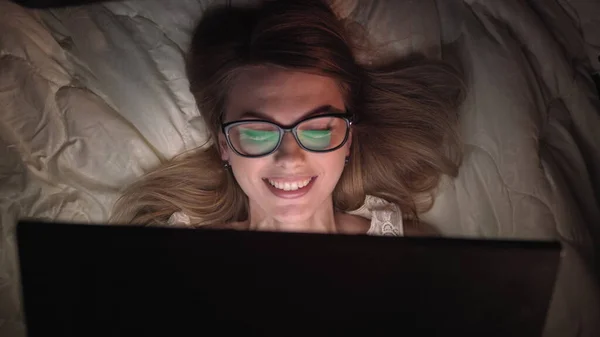 Top View Young Woman i sengen jobber på en laptop-datamaskin om natten. Student som gjør seg klar til eksamen, unntaksvis dedikert prosjektleder som fullfører arbeidet i sengen om natten. – stockfoto