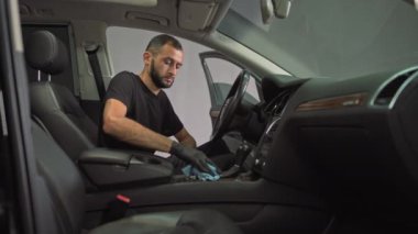 Araba yıkama, arabada oturan bir adam özel bir bronzlaştırıcı ile arabayı temizliyor, iç kısımları pislikten temizliyor, iç kısımları dezenfekte ediyor, araba yıkama işçisi