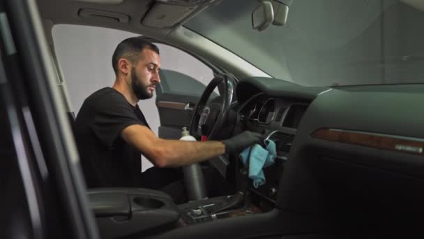 A man in a black T-shirt chemically cleans the panel of an expensive car. Dry cleaning of cars. Cleaning parts with a brush from dirt — Stock Video