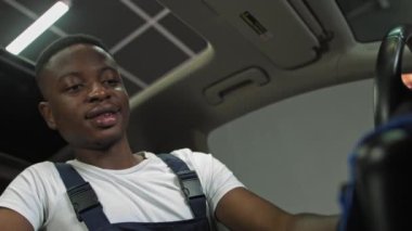Afro-Amerikalı 'nın neşeli bir portresi, iş yerinde kendine güveni olan araba vites kutusunun sapını siler, genç bir adam araba temizlemekle meşgul olur.